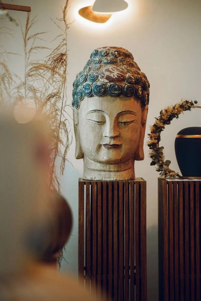 Urne und Buddhakopf auf Holzstelen in unserem Haus in Frankenthal